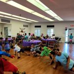Niños y adultos participando en un juego de baile en el piso durante una fiesta de cumpleaños con el Payaso Pikorete en New Smyrna Beach, Florida.